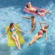Transparent floating pool mattress. There are three different color options: lime green, pink or aqua blue. This image shows people lounging on the mattresses in a pool.