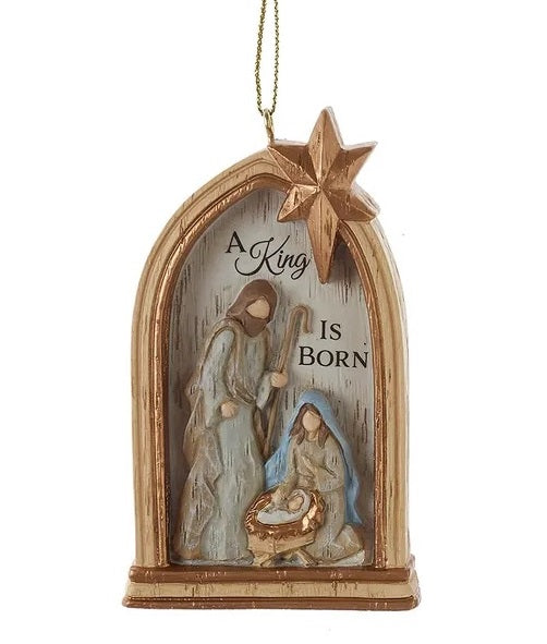 This image shows a window arch shaped ornament with Joseph and Mary watching over baby Jesus in the manger. There's a star at the top and it reads "A KING IS BORN."