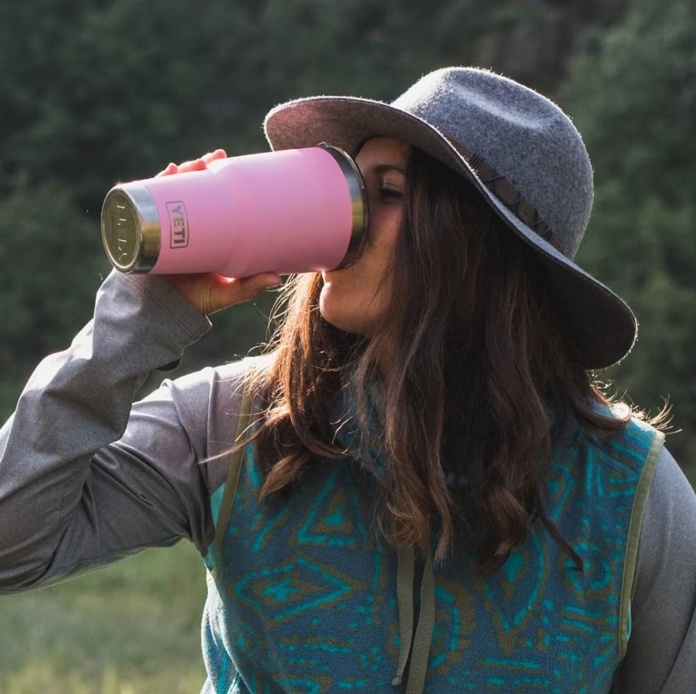 This is a lifestyle image of a woman drinking from this pink colored Yeti cup.