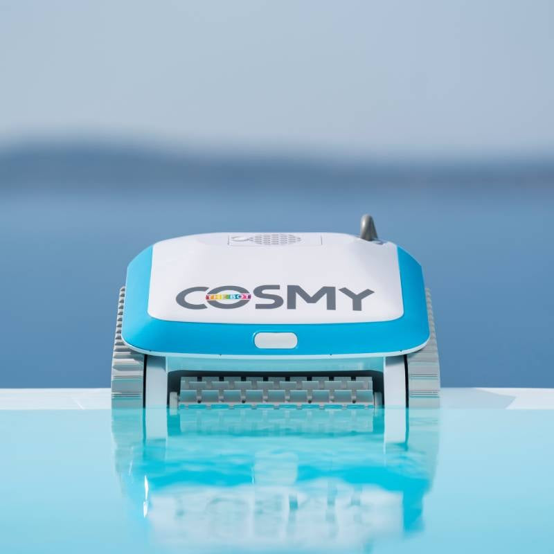 Robotic pool cleaner. Body is blue and white with gray bristles. This shows the Cosmy bot on top of some water.
