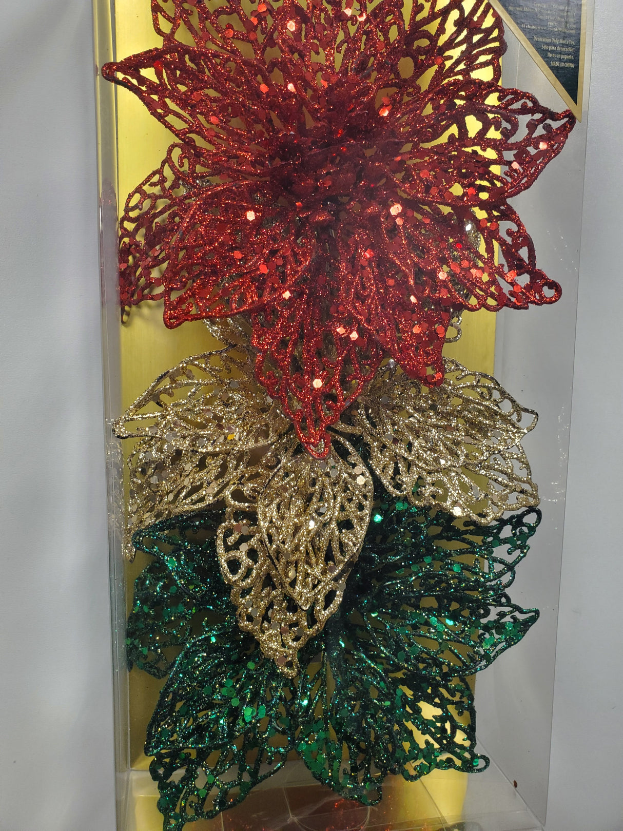 Clip on ornaments. One set of three features all red poinsettias. One set of three feature two red poinsettias and one green poinsettia. One set of three features two red poinsettias and one gold poinsettia. One set of three features one red, one gold and one green poinsettia.