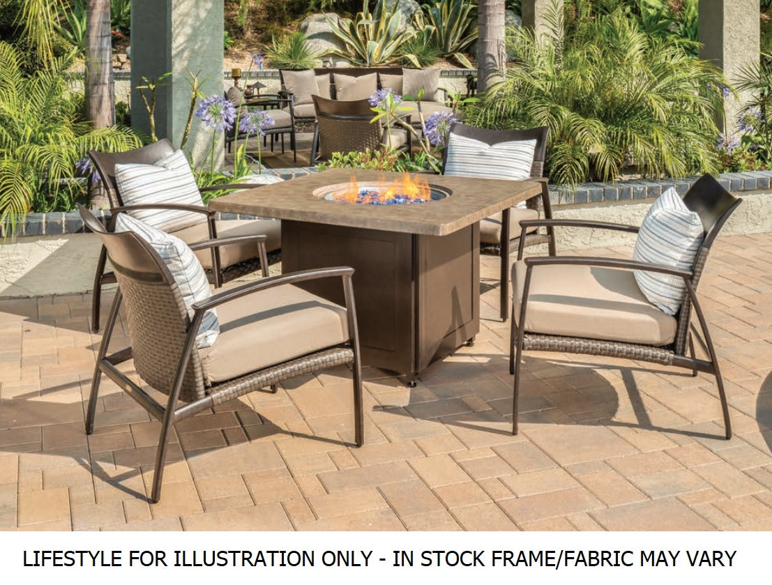 A unique looking patio set made up of four armchairs and a square fire pit table in an exotic looking backyard