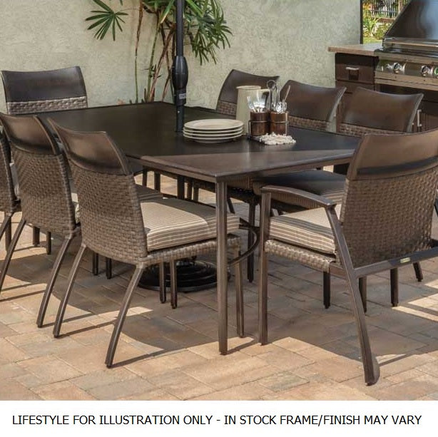 A patio dining set on an outdoor patio near a grill and a palm tree