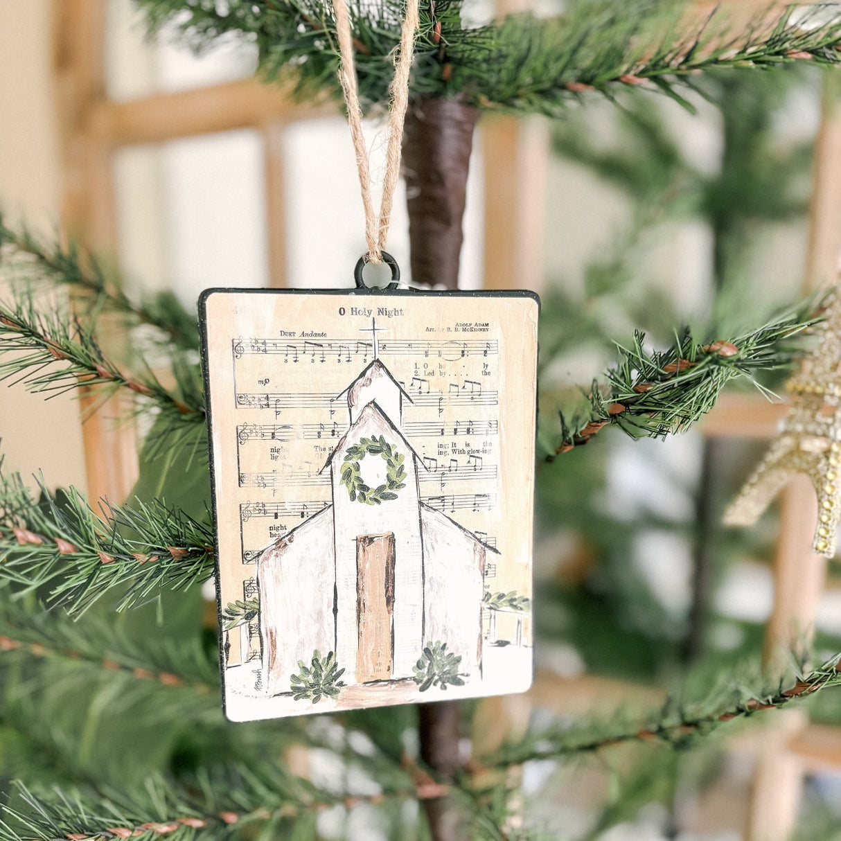 Each ornament features a background printed with sheet music; there are two options. One ornament has the sheet music for "Oh Holy Night" and a chapel with a garland at the steeple. One ornament has the sheet music for "Silent Night" and a chapel with a wreath at the steeple.