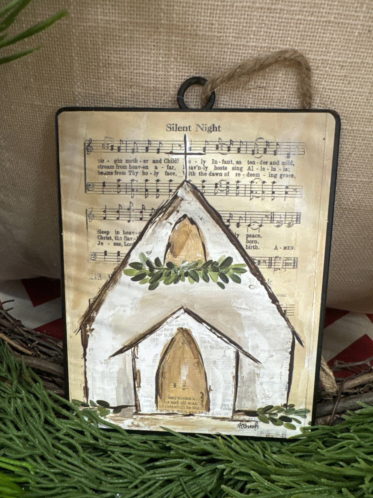 Each ornament features a background printed with sheet music; there are two options. One ornament has the sheet music for "Oh Holy Night" and a chapel with a garland at the steeple. One ornament has the sheet music for "Silent Night" and a chapel with a wreath at the steeple.