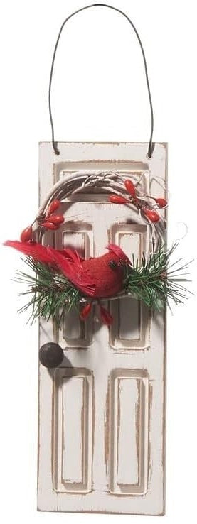 Ornament shaped like a white door. On the door is a wreath with pine needles and a cardinal accent.