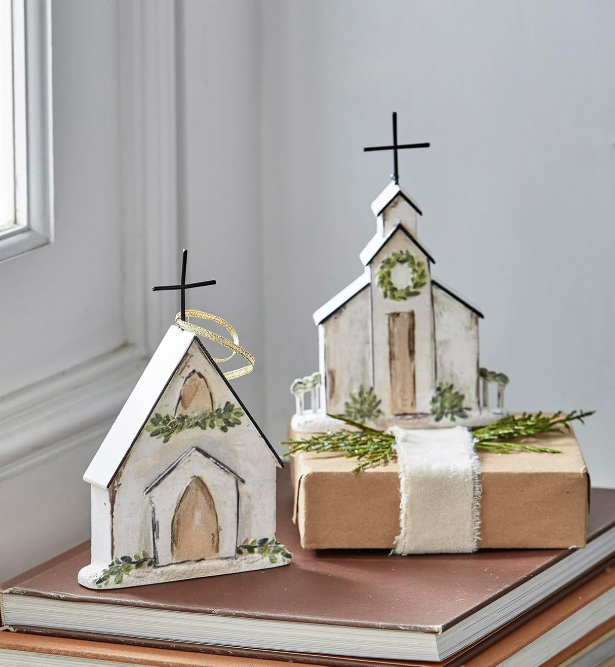 Ornament shaped like a church. One church features a wreath near the steeple. One church features a garland near the steeple.
