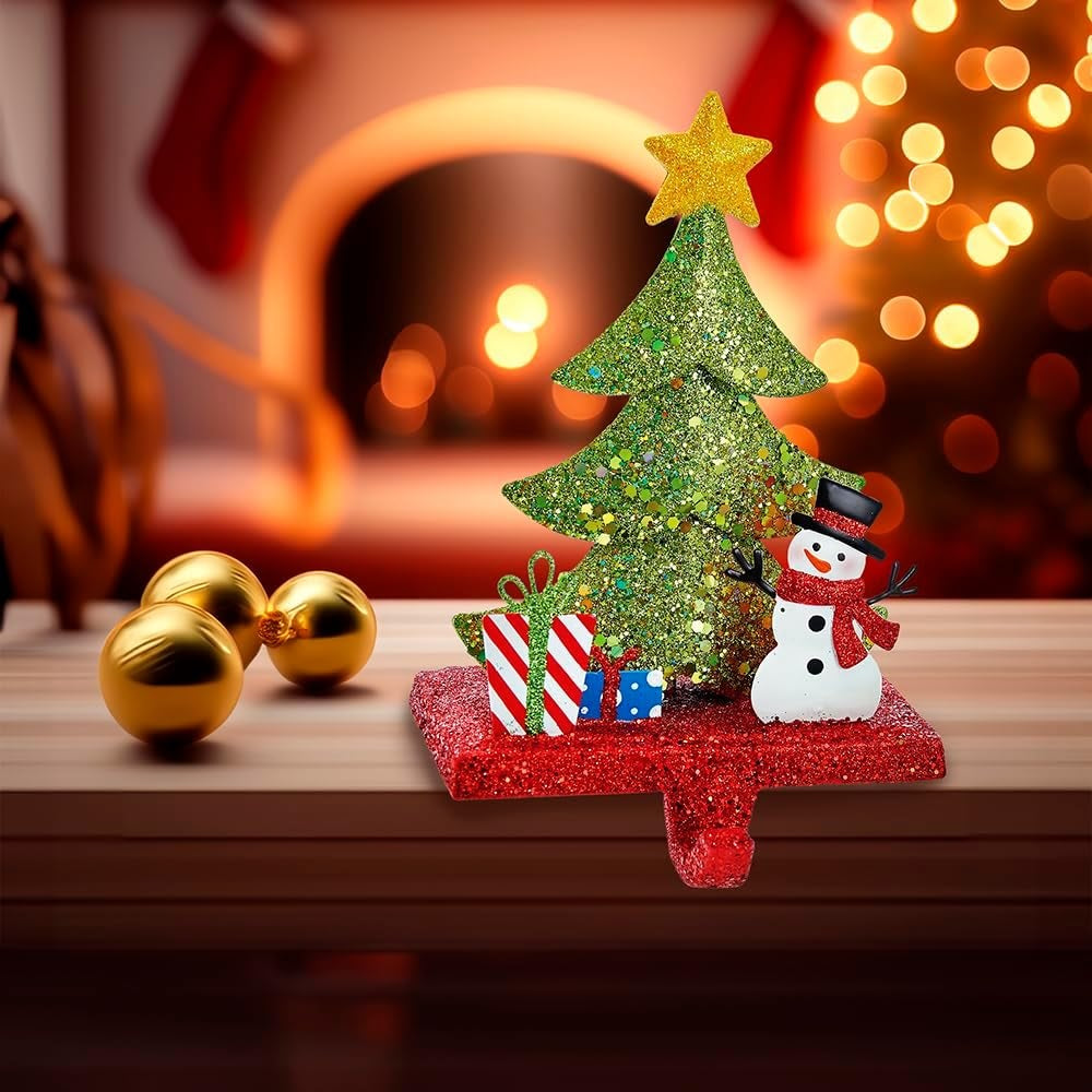 Stocking hanger covered in glitter. Designed to look like a light green tree with a yellow star on top. Next to the tree are two presents and a snowman wearing a top hat and a red scarf. The base of the holder is covered in red glitter.