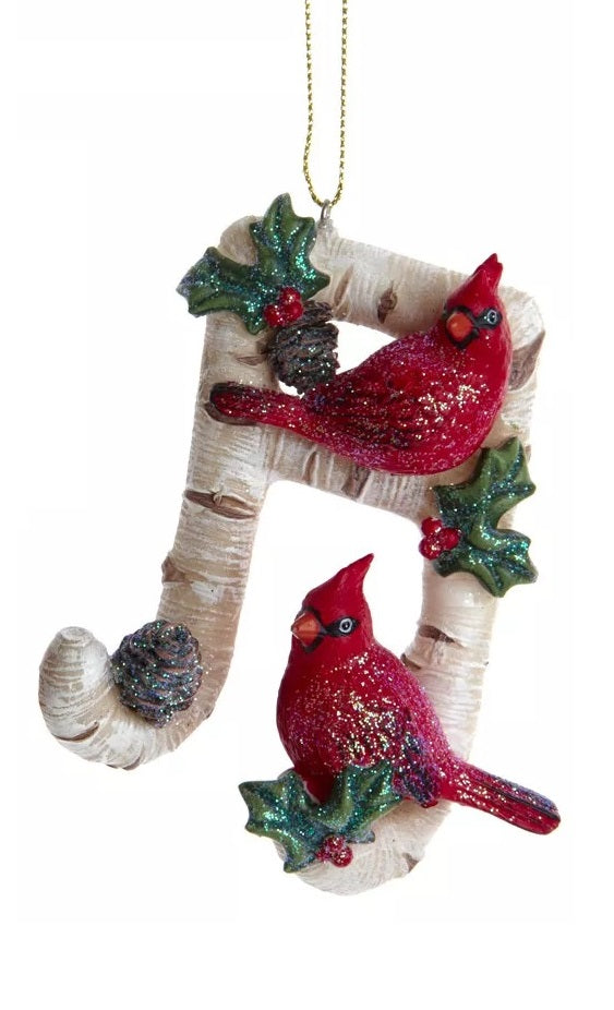 One ornament is shaped like a treble clef. One ornament is shaped like a slanted beamed sixteenth note. Each ornament is designed to look like it's made of birch tree and features glittered holly leaves, berries and pine cone accents.