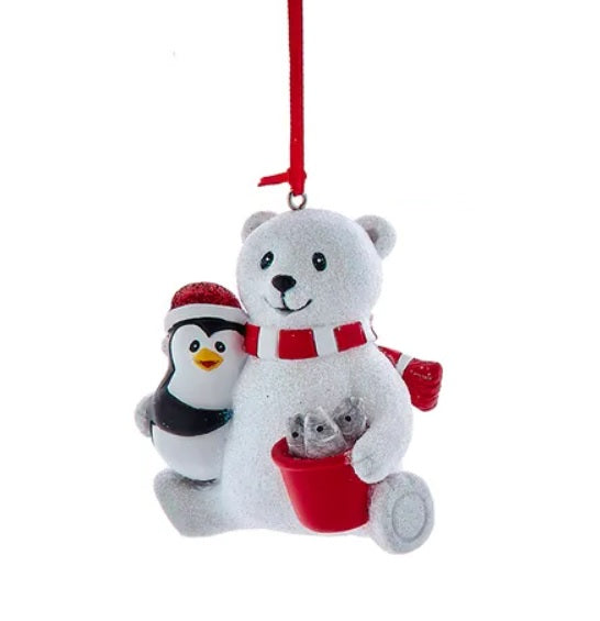 This ornament features a polar bear and a penguin smiling over a red bucket of fish. Hangs from a red ribbon.