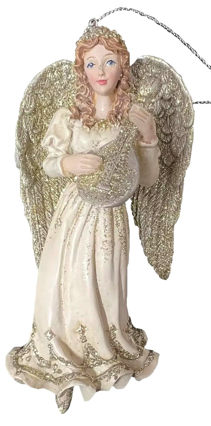 Ornament shaped like an angel holding a musical instrument. One angel is blond and holding a harp. One angel is brunette and holding a trumpet. One angel is a redhead and holding a mandolin.