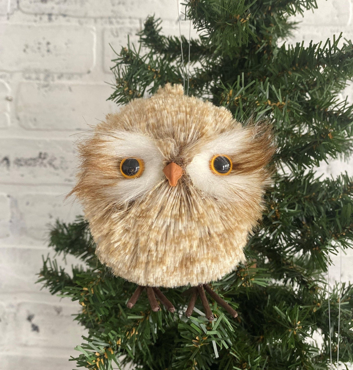 Fluffy ornament shaped like a cute owl with big, yellow/orange eyes.