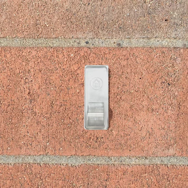 This is a lifestyle image showing the clip stuck to a brick.