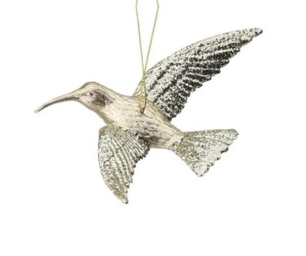 Ornament shaped like a hummingbird. The body is champagne colored and the wings are covered in gold glitter.
