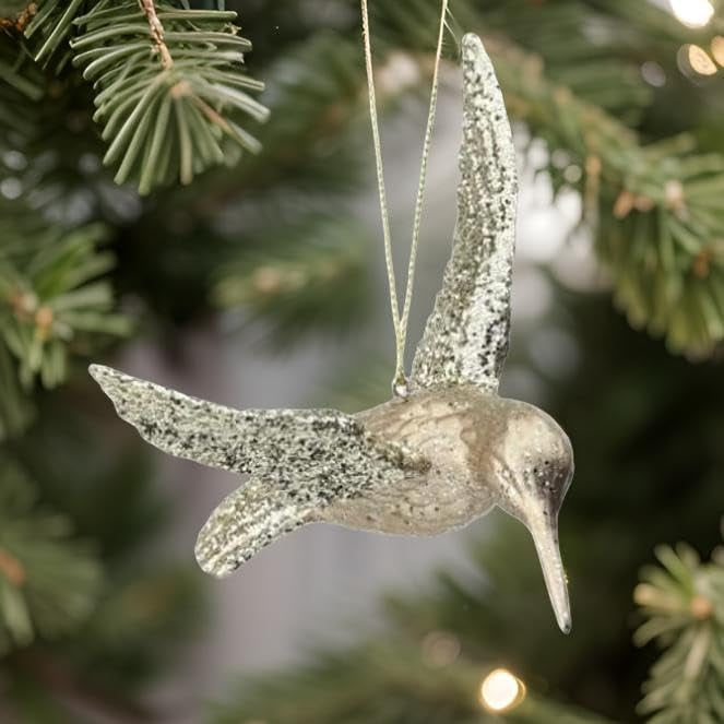 Ornament shaped like a hummingbird. The body is champagne colored and the wings are covered in gold glitter.
