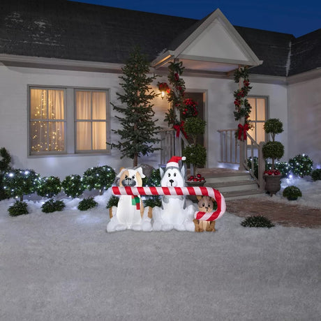 Christmas inflatable shaped like three dogs holding a giant candy cane in their mouths. One dog is wearing a red and green sweater. Another dog is wearing a Santa hat.
