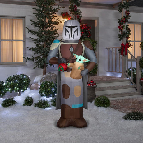 Christmas inflatable designed to look like the Star Wars characters The Mandalorian and Grogu. Mando is holding Grogu and a red holiday ornament.