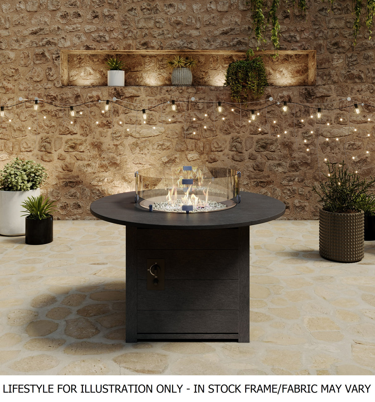 A round fire pit table on an outdoor stone porch with a stone wall and surrounded by plants