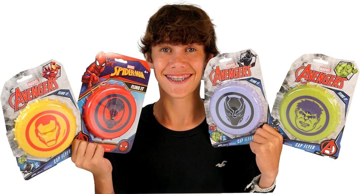 Water soaker frisbee fun summer toy. One frisbee is red and features Spiderman. One frisbee is green and features The Hulk. One frisbee is yellow and features Iron Man. One frisbee is purple and features the Black Panther. This image shows a boy with braces holding up all four options for the cap flyer.