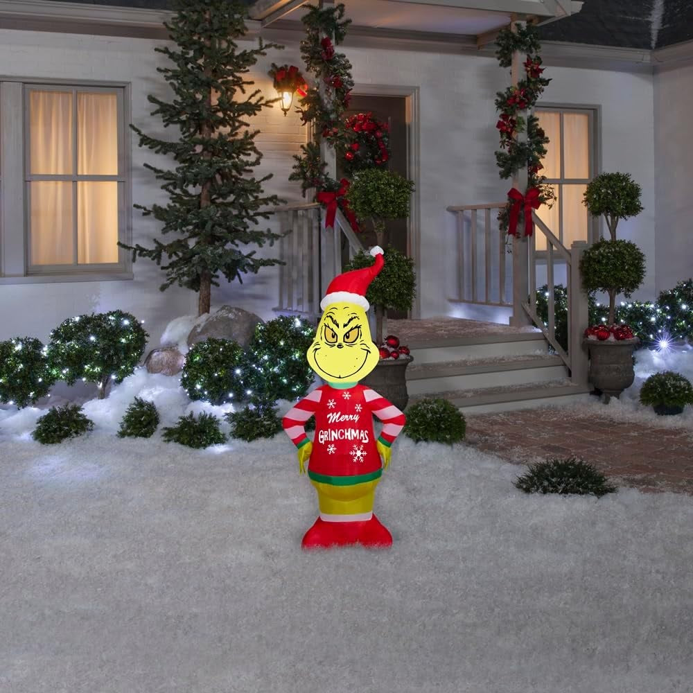 Christmas inflatable shaped like the cartoon character The Grinch. The Grinch is wearing a Santa hat and an "ugly" sweater that reads "Merry Grinchmas." The sleeves on the sweater are red and white striped.