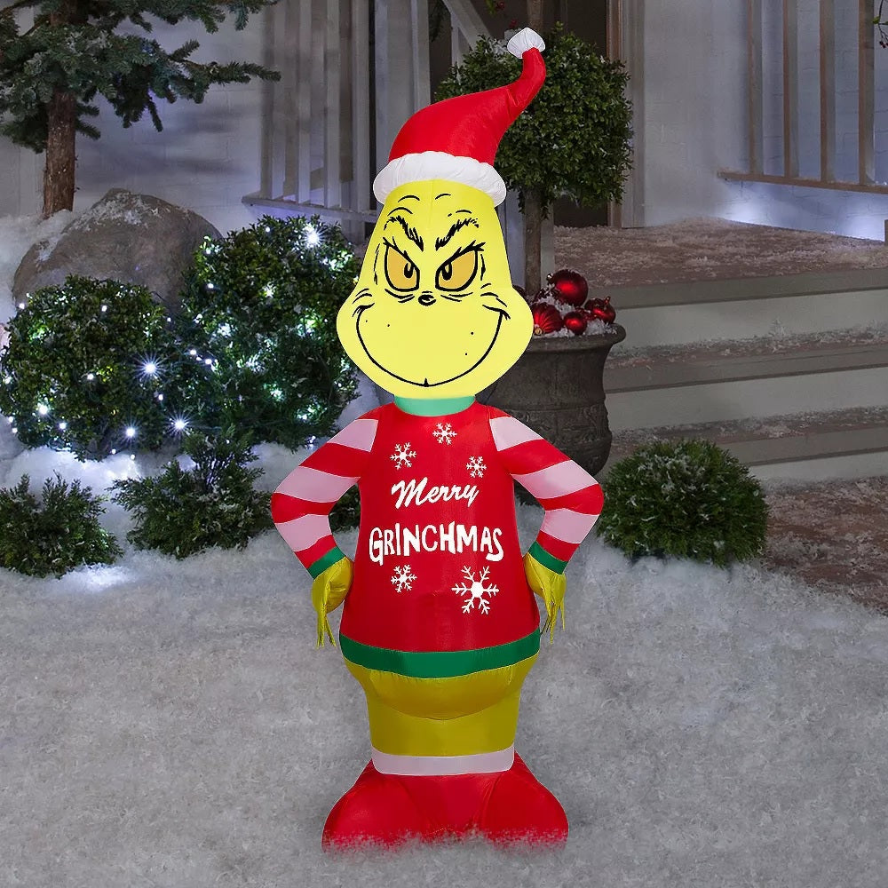 Christmas inflatable shaped like the cartoon character The Grinch. The Grinch is wearing a Santa hat and an "ugly" sweater that reads "Merry Grinchmas." The sleeves on the sweater are red and white striped.