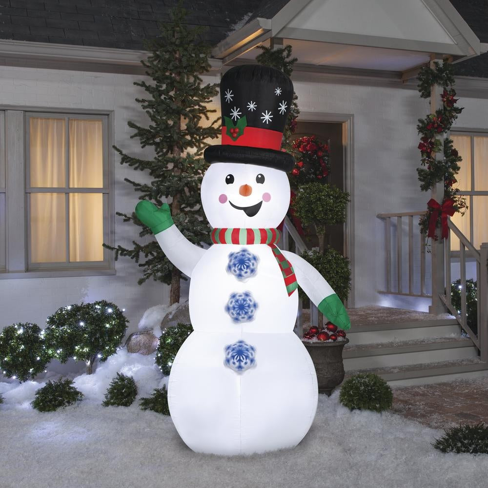 Inflatable snowman wearing a top hat, a red and green striped scarf and green gloves. There are buttons shaped like snowflakes going down his belly. The buttons spin!