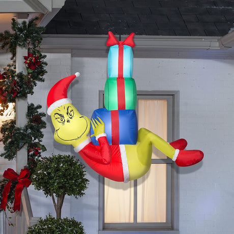 Christmas inflatable designed to look like The Grinch dressed as Santa and hanging from a rope, holding presents.