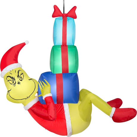 Christmas inflatable designed to look like The Grinch dressed as Santa and hanging from a rope, holding presents.