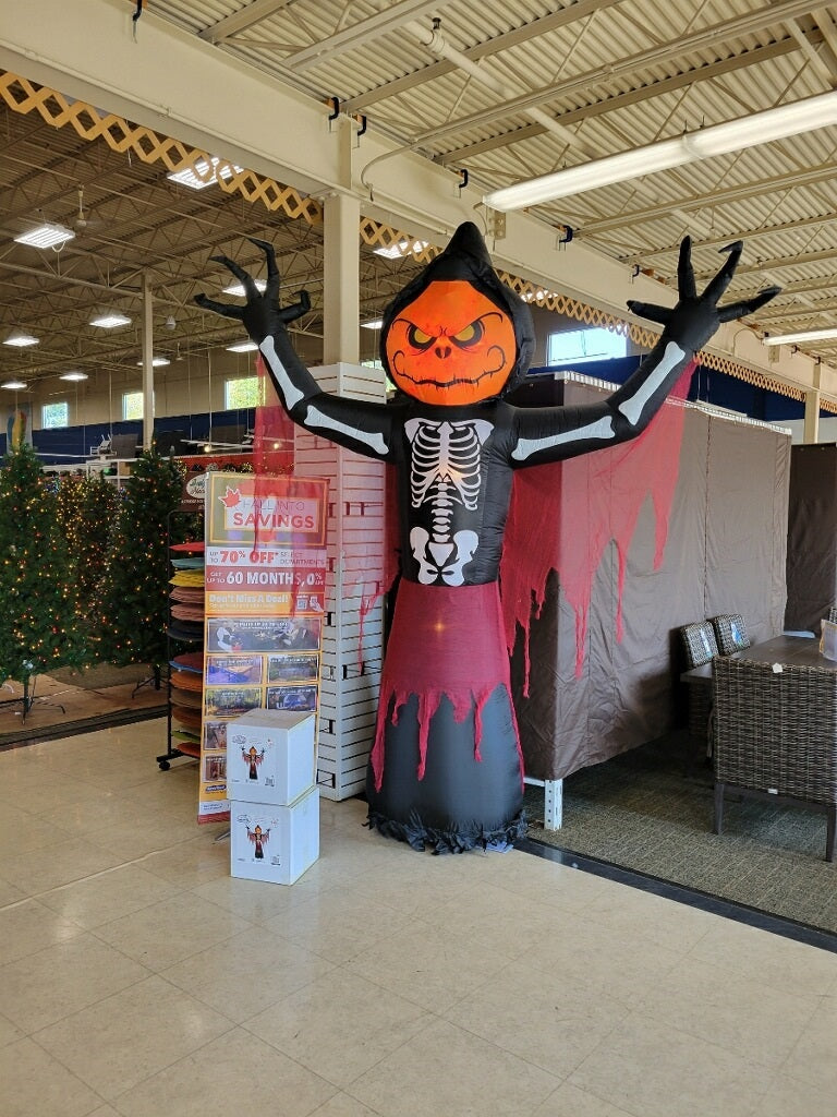 Halloween inflatable. The head is a spooky jack-o-lantern, the body is a skeleton and it's wearing a black robe with red dangling off of it. It lights up from the inside.