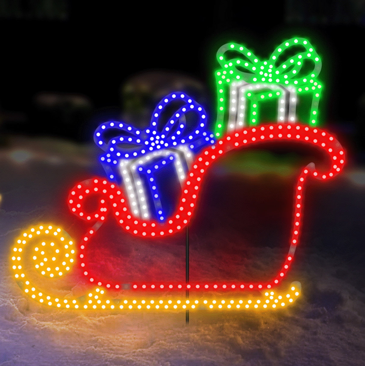 Outdoor LED Christmas decoration shaped like a sleigh with presents inside. It's lit with blue, pure white, green and yellow lights.