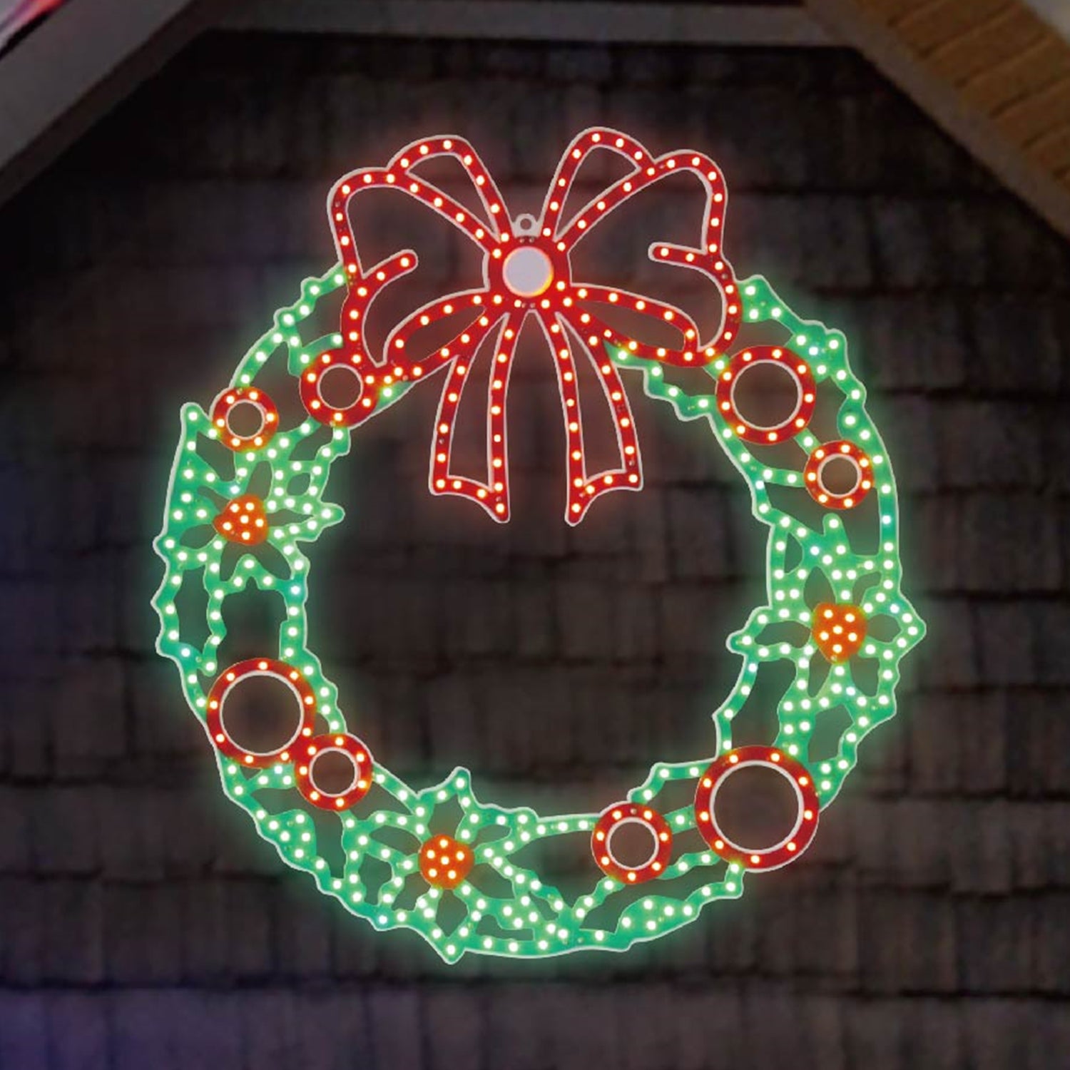 Outdoor LED decoration shaped like a wreath decorated with a red bow and berries. The lights are red and green.
