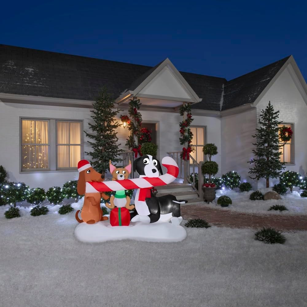 Christmas inflatable designed to look like three dogs sharing a giant candy cane. One dog is wearing a Santa hat, another one is sitting on a present and the third is wearing a red scarf.