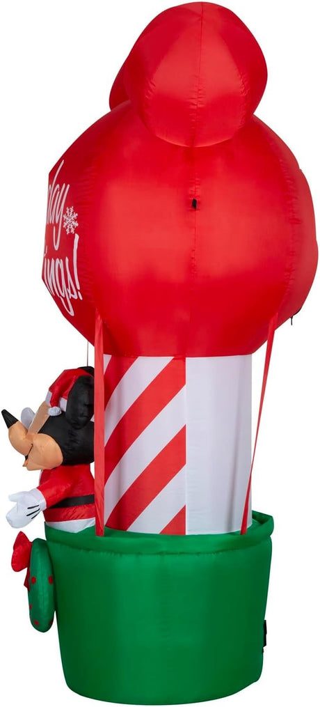 Christmas inflatable shaped like Mickey Mouse dressed as Santa and standing in a hot air balloon basket. The basket is green with a green wreath on it. The balloon is shaped like Mickey's head and ears. The balloon reads "Holiday Greetings!"