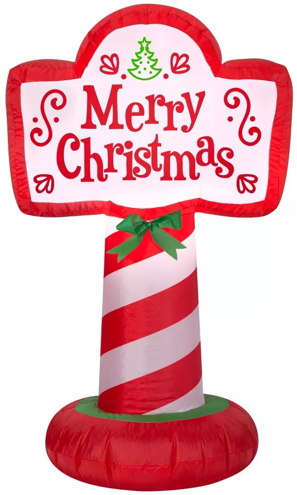 Christmas inflatable shaped like a sign that reads "Merry Christmas." The pole is red and white striped, it features a green bow and there are cute swirl accents on the sign.