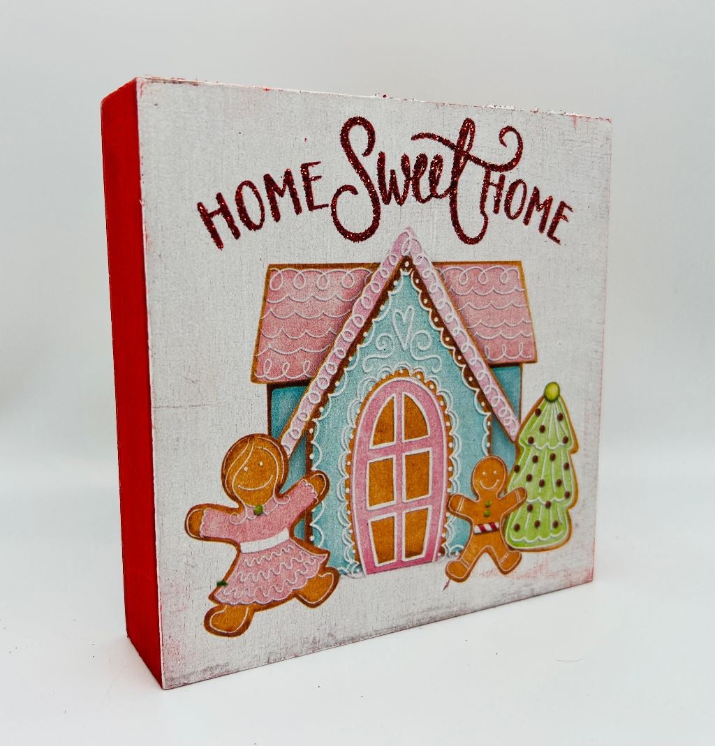 One sign features two gingerbread people outside of a gingerbread house and reads "Home Sweet Home." One sign reads "Joy to the World" and has some gingerbread cookie accents. One sign reads "Hot Cocoa Served Daily" and features a mug with cookies and a candy cane inside. One sign reads "Sip and Enjoy" and features two mugs with different designs.