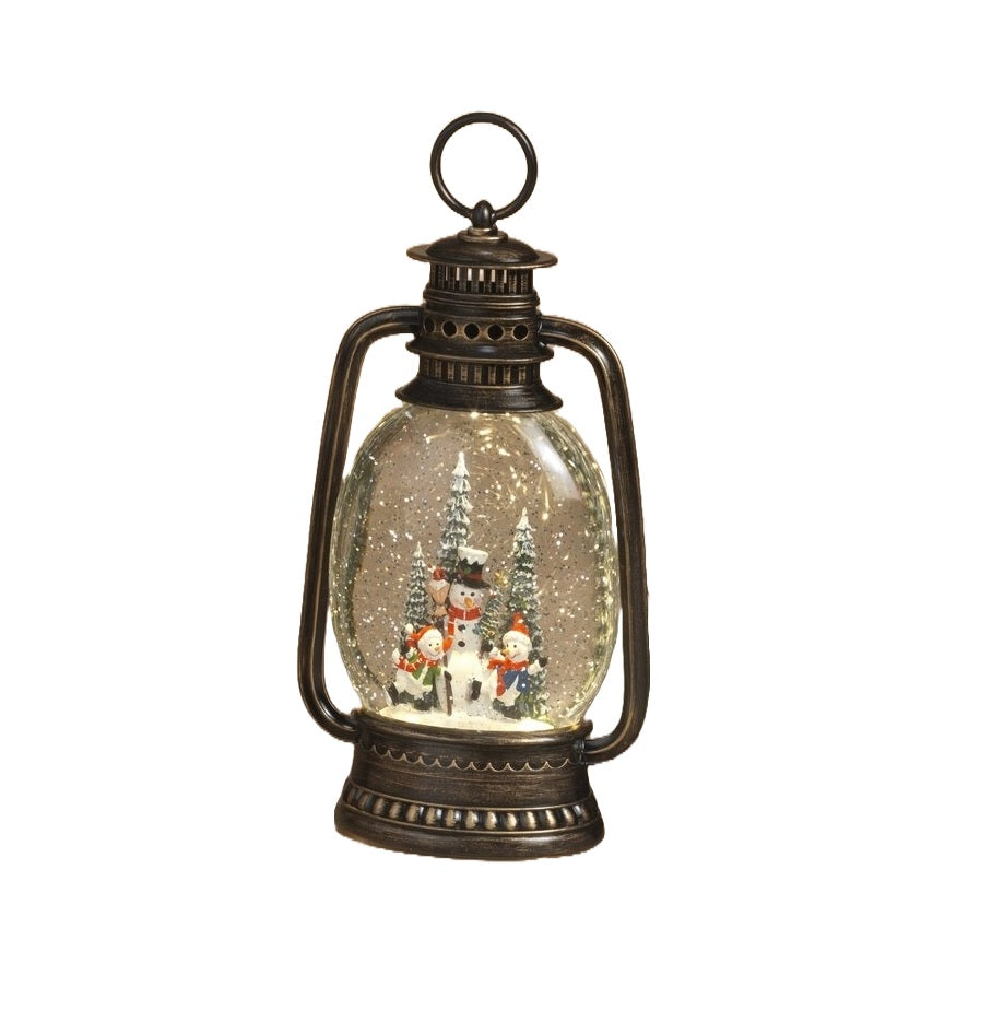 Lighted holiday spinning water globe lantern. This lantern has a snowman family surrounded by trees.