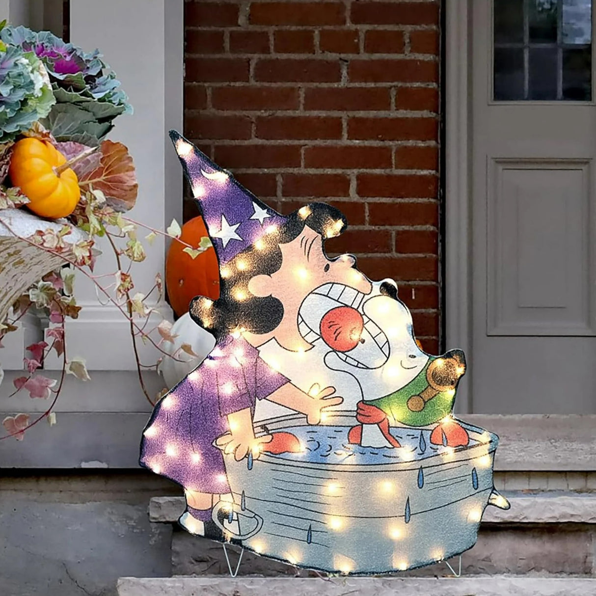 Lighted Halloween decoration. Looks like Lucy and Snoopy from the Peanuts cartoons bobbing for apples. Lucy is dressed in a pointed, purple hat and dress. Snoopy appears to be dressed as a pilot. Snoopy is inside the small water tub.