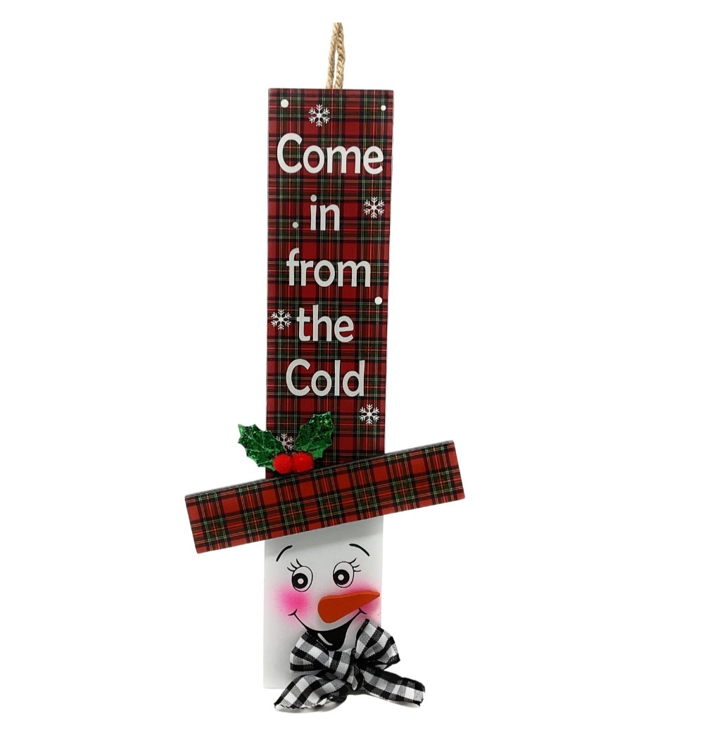 Hanging sign designed to look like a snowman head. One snowman has a red and green buffalo check top hat that reads "Let It Snow." One snowman has a red and green plaid top hat that reads "Come in from the Cold." One snowman has a red and white plaid top hat that reads "There's Snow place like Home."