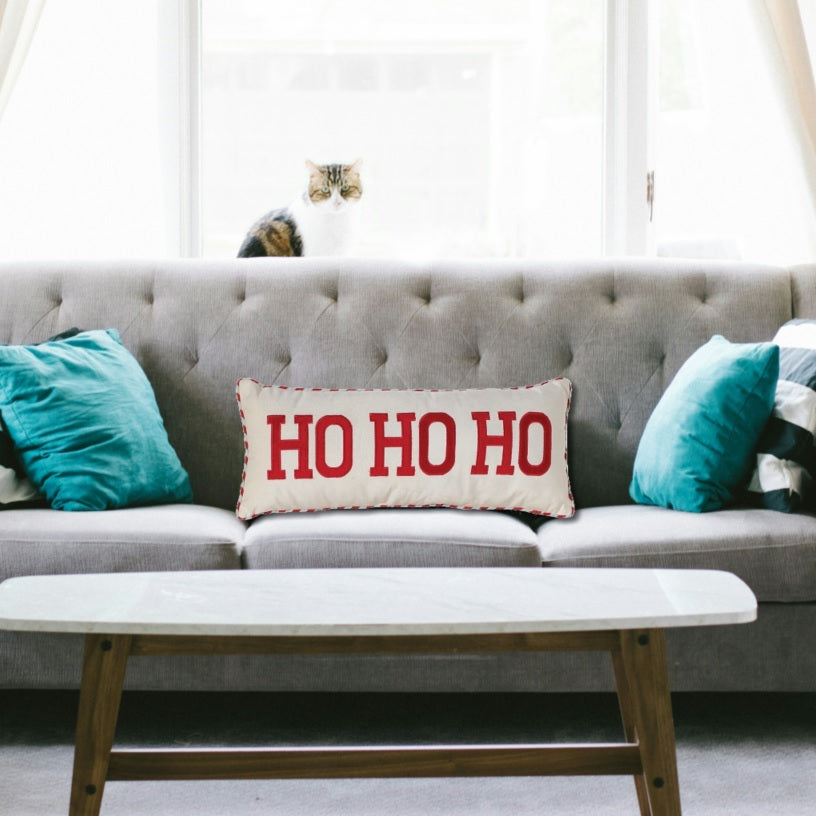 White pillow that reads "HO HO HO" in red, block text. The border is red and white striped.