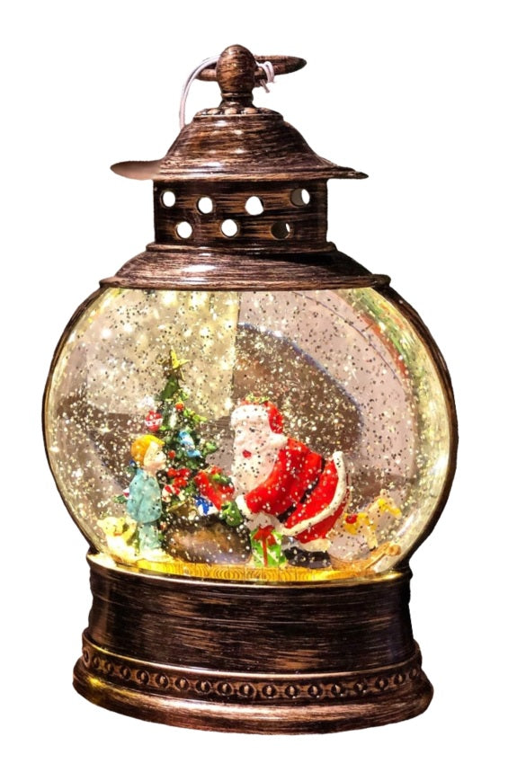 Glass globe lantern tabletop decoration. Inside this lantern is glitter and a winter scene showing Santa handing presents to a young child.