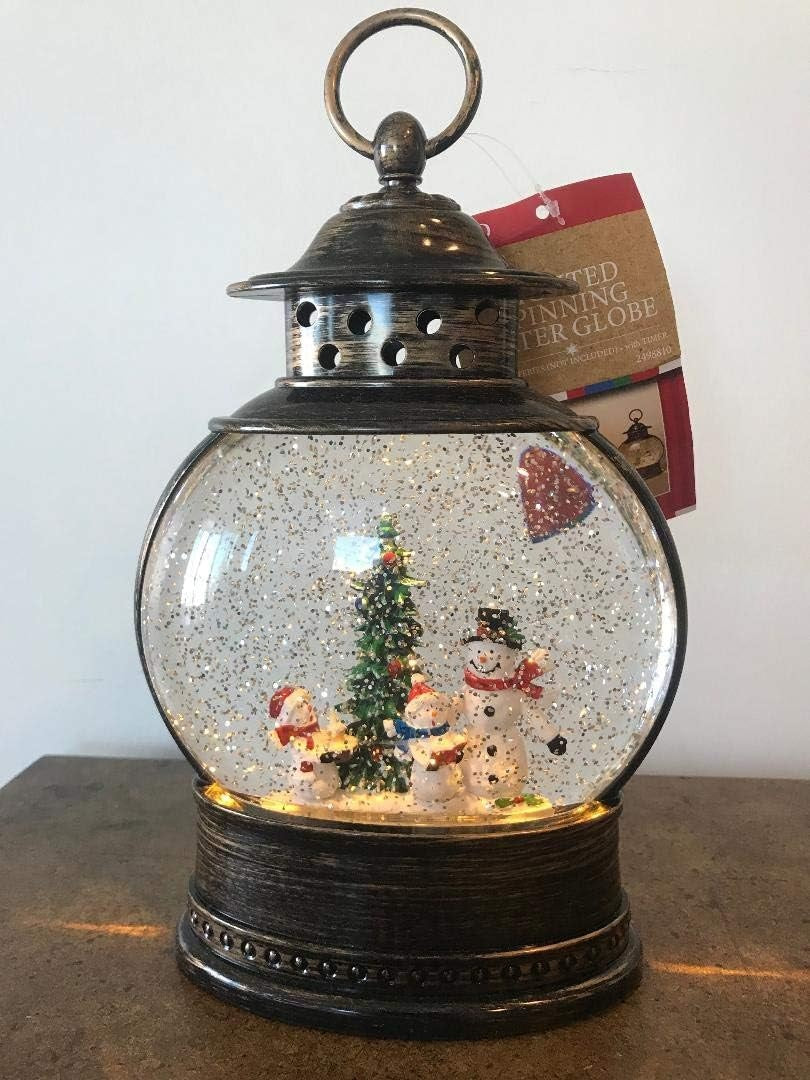 Glass globe lantern tabletop decoration. Inside this lantern is glitter and a winter scene showing three snowmen standing near a decorated tree.