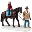 Resin figurine for a Lemax display. Designed to look like a man holding the reins of a brown horse. There's a young child riding the horse and wearing a helmet. They're both wearing winter clothes.