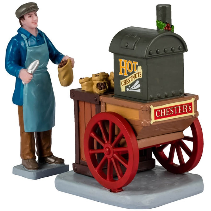 Resin figurine for a Lemax Village display. Designed to look like a roasted chestnut vendor. The cart reads "Chester's Hot Chestnuts."