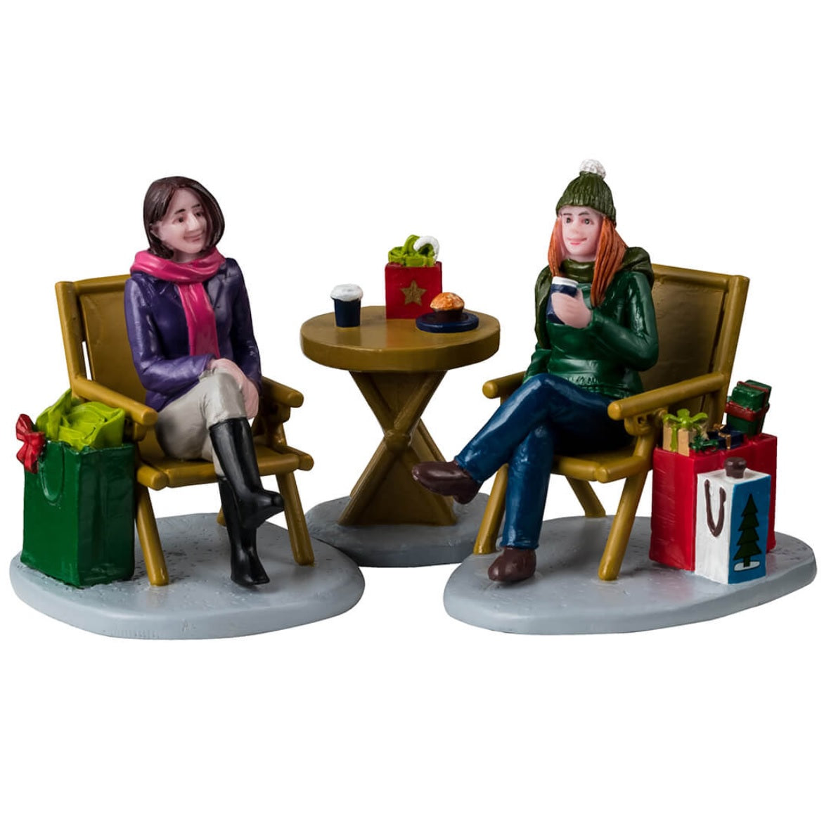 Resin figurines for a Lemax Village tabletop display. Designed to look like two women enjoying a cup of coffee. They're both sitting in chairs, there's a small, round table in between them. They're both wearing winter clothes and have shopping bags next to them.
