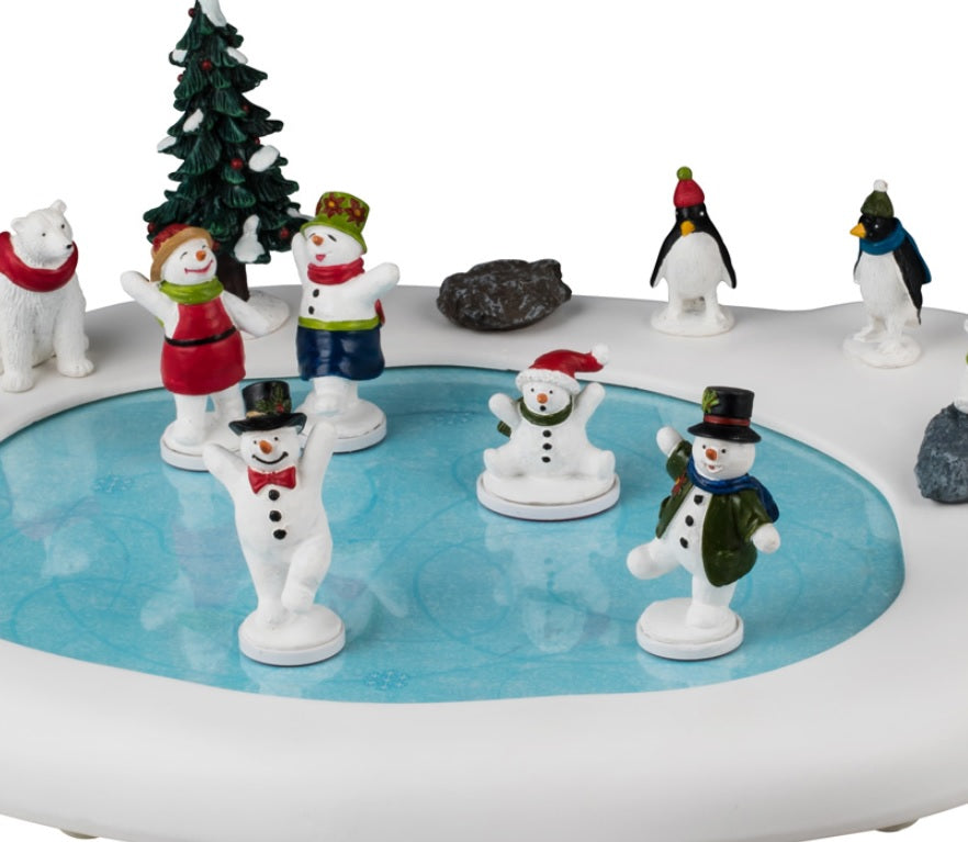Animated resin table accent for a Lemax display. Designed to look like a frozen pond surrounded by snow and a few rocks. There are five snow people skating on the ice, all wearing winter clothes. There are three polar bears and two penguins watching. The animals are all wearing either a winter hat or a scarf.