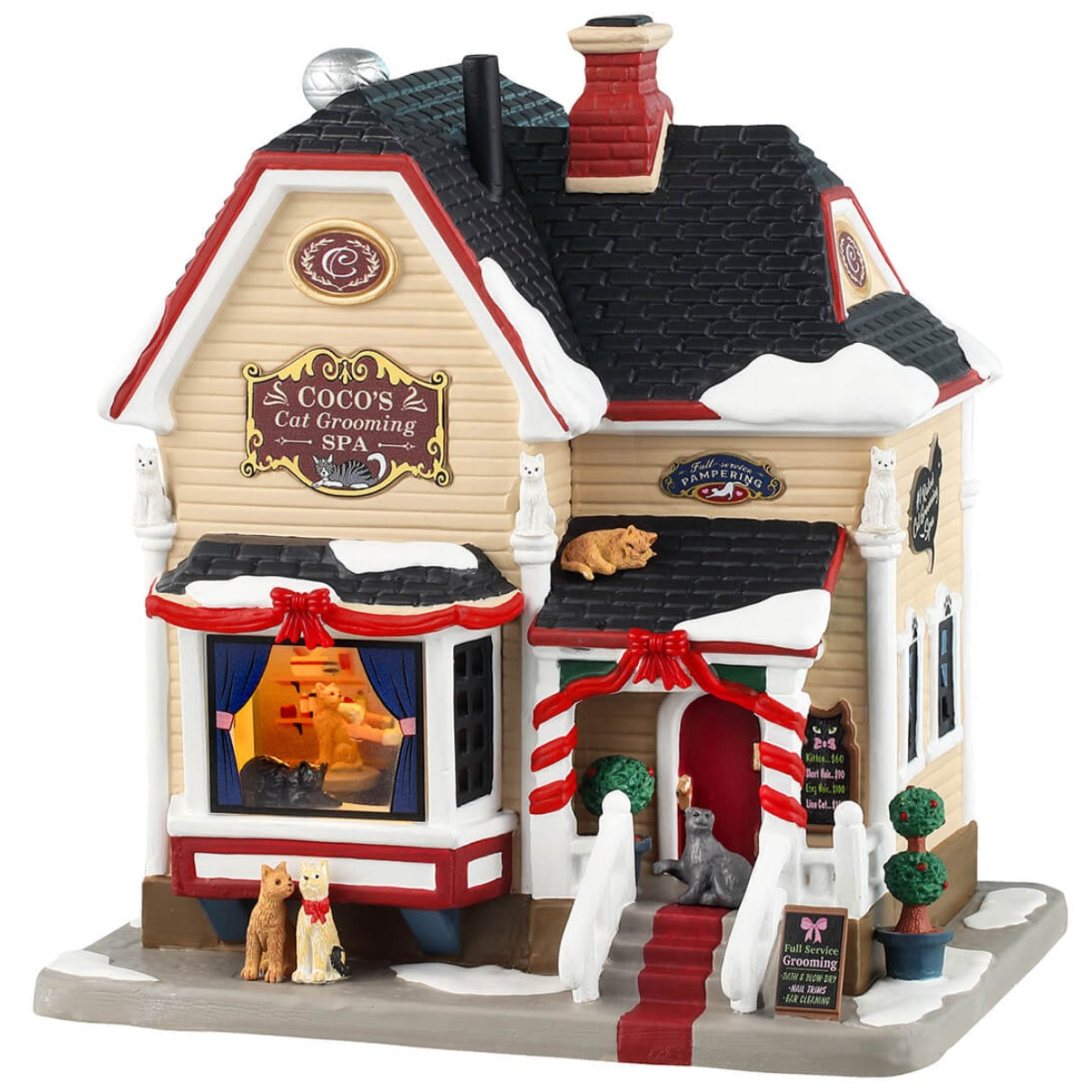 Porcelain lighted building for a Lemax display. Designed to look like a Victoria-era house that's been turned into a cat grooming office. There's snow on the roof and the sidewalk. There are different colored cats all over the place. Inside the window, you can see one of the groomers hard at work. There are red ribbon accents and two small potted trees.