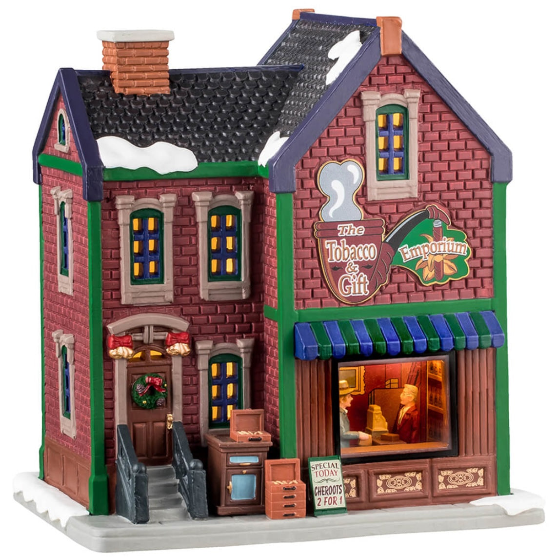 Porcelain lighted building for a Lemax display. Designed to look like a brick building with snow on the roof and the sidewalk. The signs read "The Tobacco & Gift Emporium" and "Special Today: Cheroots 2 for 1." There's a decorated wreath on the door. Through the window in the front, you can see a man buying cigars from a man behind a counter.
