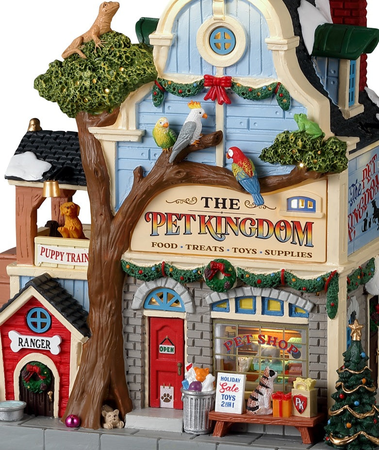 Resin building for a Lemax display. Designed to look like a pet store. There's a big tree in front and features a lizard on top, three exotic birds and a dog at the base. There are dogs off to the side in the "Puppy Training" balcony. The shop is decorated for Christmas.