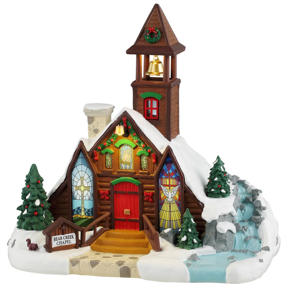 Resin lighted building for a Lemax display. Designed to look like a brown, wooden chapel with a stone chimney and a bell tower. The roof and the ground is covered in snow. There's a wreath on the bell tower, garland on the roof and two red bows on the sides of the door. The windows are stained glass. One of them is a yellow cross with a blue background. The other is a white dove with a yellow glow. There's a waterfall on the side.