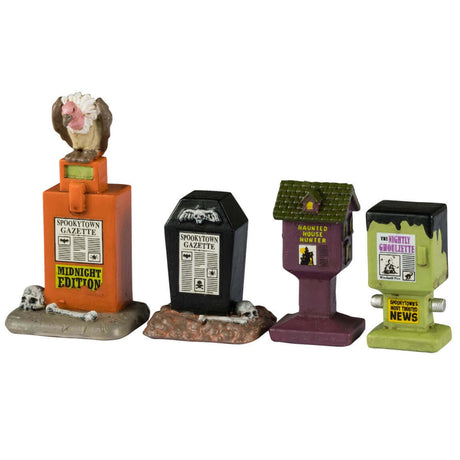 Resin village accents for a Lemax display. Designed to look like public newspaper boxes. One is orange and reads "Midnight Edition" and has a vulture sitting on top. The next one is black and shaped like a coffin. One is purple and a dark green and shaped like a birdhouse. The last one is shaped like Frankenstein's head.